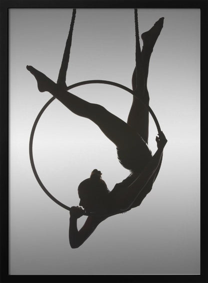 A black silhouette of a graceful female acrobat in an inverted pose on a suspended aerial hoop, set against a light grey background. Print