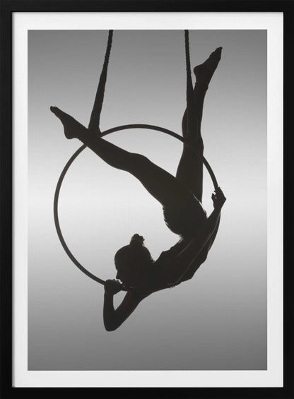 A black silhouette of a graceful female acrobat in an inverted pose on a suspended aerial hoop, set against a light grey background. Print