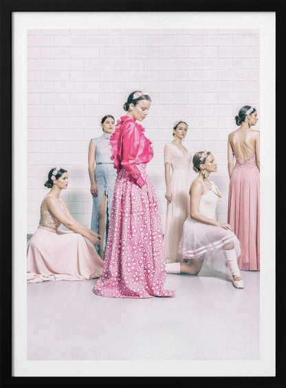 A studio photograph of six young women in elegant pastel gowns posing against a white brick wall. The central figure wears a vibrant pink ruffled blouse and a patterned maxi skirt, while the others are dressed in light pink, white, and pale blue dresses, some with ballet-inspired elements. They all have flowers in their hair, creating a soft, high-fashion aesthetic. Print