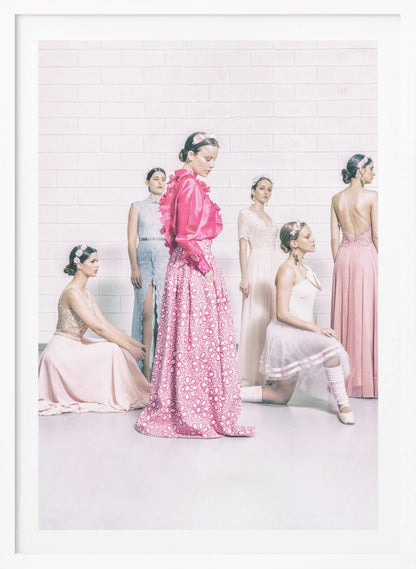 A studio photograph of six young women in elegant pastel gowns posing against a white brick wall. The central figure wears a vibrant pink ruffled blouse and a patterned maxi skirt, while the others are dressed in light pink, white, and pale blue dresses, some with ballet-inspired elements. They all have flowers in their hair, creating a soft, high-fashion aesthetic. Print
