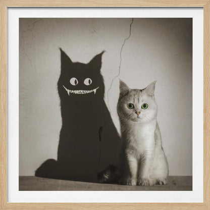 A photographic artwork of a cute, silver-grey cat with vibrant green eyes sitting beside its shadow, which is distorted into a monstrous black creature with large white eyes and a sharp, toothy grin against a cracked wall. Decor