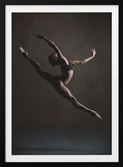 A dramatic, low-key studio photograph of a muscular female dancer captured mid-leap. She is in a full split, arching her back with her arms extended gracefully. The lighting accentuates her toned physique against a dark, textured brown background. Poster