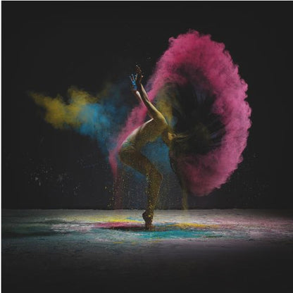 A dynamic photo of a dancer arching backward, their long hair creating a massive arc of vibrant pink powder against a black background, with smaller bursts of blue and yellow. Decor