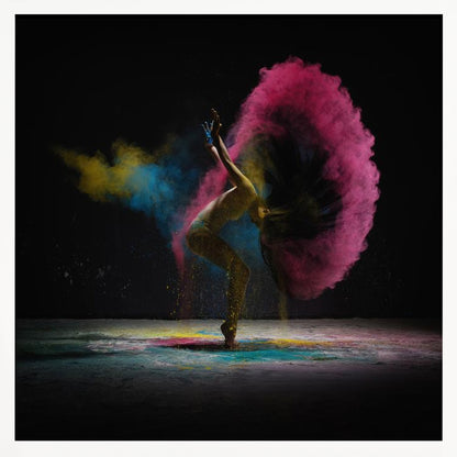 A dynamic photo of a dancer arching backward, their long hair creating a massive arc of vibrant pink powder against a black background, with smaller bursts of blue and yellow. Decor