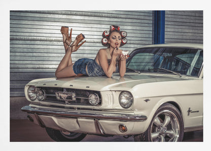 A woman in a retro pin-up style lies on the hood of a vintage white Ford Mustang in a garage, applying red lipstick with her hair set in soda can curlers. Poster