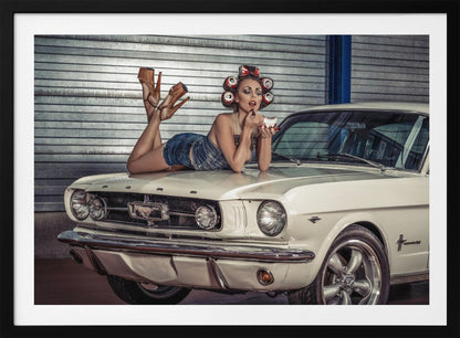 A woman in a retro pin-up style lies on the hood of a vintage white Ford Mustang in a garage, applying red lipstick with her hair set in soda can curlers. Poster