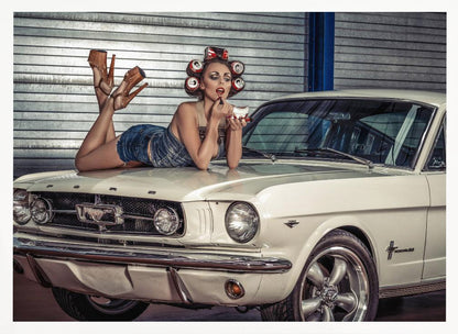 A woman in a retro pin-up style lies on the hood of a vintage white Ford Mustang in a garage, applying red lipstick with her hair set in soda can curlers. Poster
