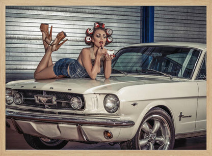 A woman in a retro pin-up style lies on the hood of a vintage white Ford Mustang in a garage, applying red lipstick with her hair set in soda can curlers. Poster
