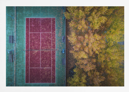 An aerial top-down photograph of a red and green tennis court covered in fallen leaves, adjacent to a dense grove of trees with vibrant yellow and gold autumn foliage, all enclosed in a silver frame. Wall Art