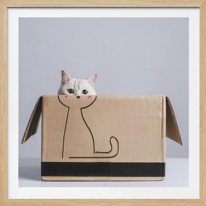 A cute white cat with green eyes peeks out of a cardboard box. The front of the box has a simple black line drawing of a cat's body, making it look as if the real cat's head belongs to the drawing. The image is set against a light gray background and enclosed in a light wood frame. Wall Art