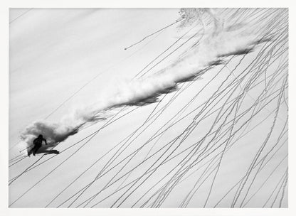 A dramatic black and white overhead photograph of a skier carving down a steep, powder-filled mountain slope, kicking up a huge plume of snow. Numerous ski tracks crisscross the pristine white snow, creating a pattern of dark lines. Poster