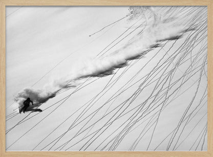 A dramatic black and white overhead photograph of a skier carving down a steep, powder-filled mountain slope, kicking up a huge plume of snow. Numerous ski tracks crisscross the pristine white snow, creating a pattern of dark lines. Poster