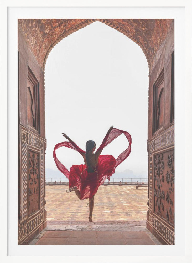 A woman in a flowing red dress dances joyfully, framed by an ornate, carved archway. Seen from behind, she leaps with her arms outstretched, holding a long red scarf that forms a heart shape around her against a bright, hazy sky. Poster