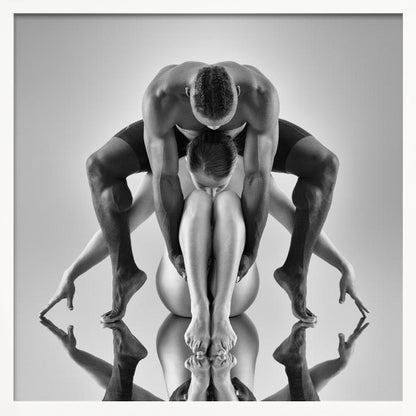 A framed black and white studio photograph of two dancers, a man and a woman, creating a symmetrical pose. The muscular man is positioned over the woman who is curled up beneath him. Their limbs are extended and reflected on the mirrored surface below, forming an abstract and powerful composition. Decor