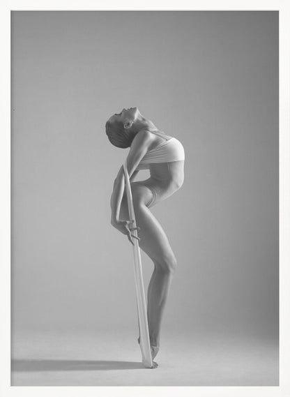 A framed black and white photograph of a graceful female dancer arching her back dramatically. She holds a long white elastic band that stretches down her body to her foot, emphasizing her athletic form and flexibility against a plain studio background. Print