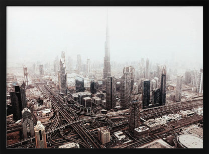 An aerial photograph of a sprawling modern cityscape on a hazy day, framed in silver. The iconic Burj Khalifa stands tall in the center background, surrounded by numerous other skyscrapers and a complex network of highways and interchanges in the foreground, all rendered in a muted, slightly sepia-toned color palette. Print
