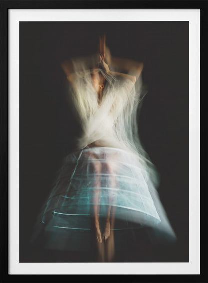 An ethereal, long-exposure photograph of a dancing figure against a dark gray background. The motion blur creates a ghostly effect, with white, gauzy fabric swirling around the upper body. The figure wears a transparent crinoline hoop skirt, revealing her legs and feet. Artwork