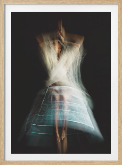 An ethereal, long-exposure photograph of a dancing figure against a dark gray background. The motion blur creates a ghostly effect, with white, gauzy fabric swirling around the upper body. The figure wears a transparent crinoline hoop skirt, revealing her legs and feet. Artwork