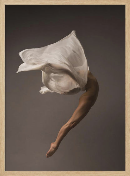 A minimalist fine art photograph of a dancer in mid-air against a solid grey background. The dancer's body is arched backwards, with a large piece of flowing white fabric enveloping their torso and creating a sense of dynamic, weightless motion. Only their muscular leg and pointed foot are clearly visible, emphasizing grace and form. Wall Art