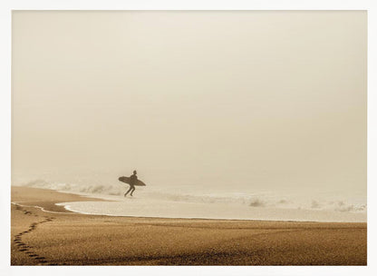 A minimalist photograph of a silhouetted surfer carrying a surfboard, running into the ocean on a foggy morning. The scene has a warm, sepia tone, with footprints visible in the wet sand in the foreground and a vast, misty sky. Wall Art