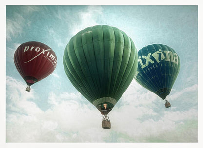 A low-angle photograph of three colorful hot air balloons floating in a cloudy blue sky, presented in a silver frame. A large green balloon is in the center, with a red balloon on the left and a dark blue balloon on the right, all featuring logos. Wall Art