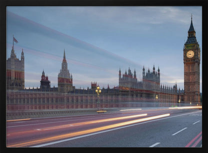 A framed, long-exposure photograph of London's Big Ben and the Houses of Parliament at dusk. In the foreground, streaks of red and yellow light from moving traffic blur across a bridge, creating a dynamic contrast with the historic architecture against a twilight sky. Decor