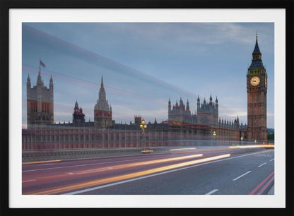 A framed, long-exposure photograph of London's Big Ben and the Houses of Parliament at dusk. In the foreground, streaks of red and yellow light from moving traffic blur across a bridge, creating a dynamic contrast with the historic architecture against a twilight sky. Decor