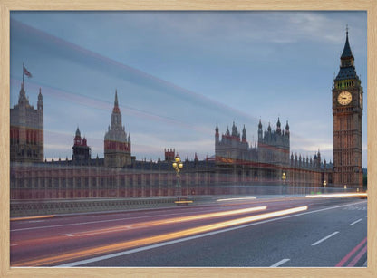 A framed, long-exposure photograph of London's Big Ben and the Houses of Parliament at dusk. In the foreground, streaks of red and yellow light from moving traffic blur across a bridge, creating a dynamic contrast with the historic architecture against a twilight sky. Decor