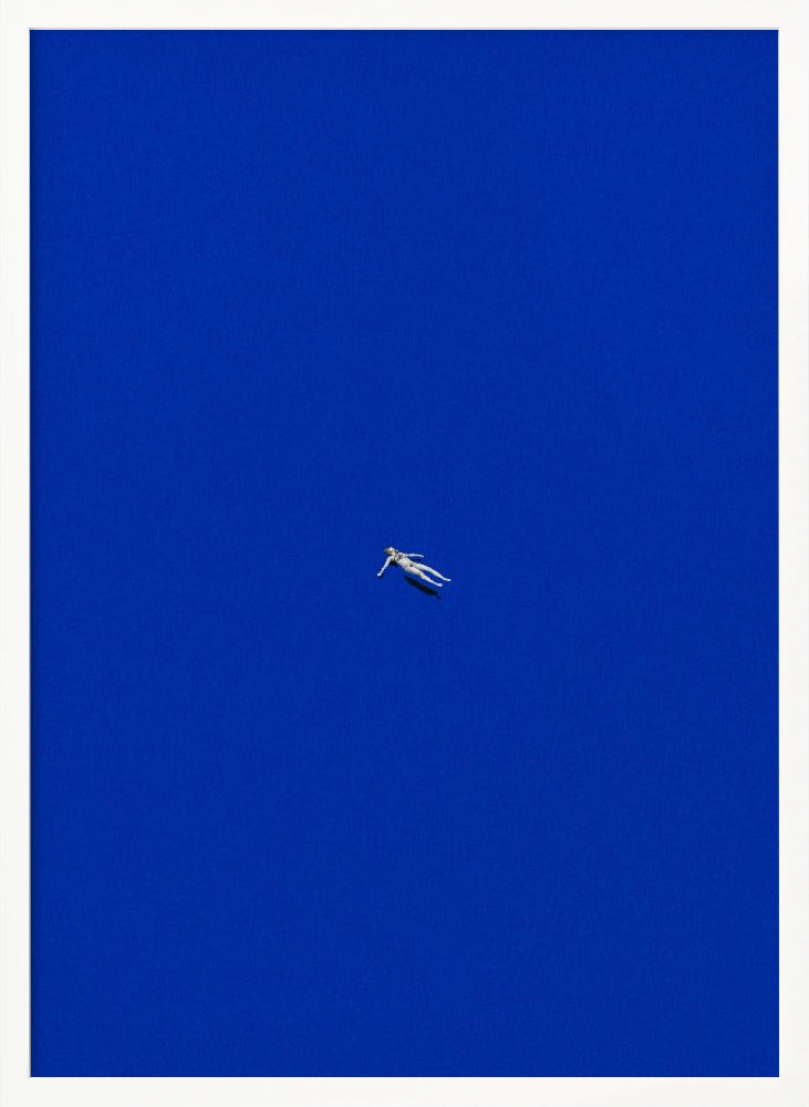 A minimalist and surreal artwork featuring a tiny, pale human figure floating peacefully in the center of an immense, solid, and vibrant blue void, all enclosed within a thin black frame. Wall Art