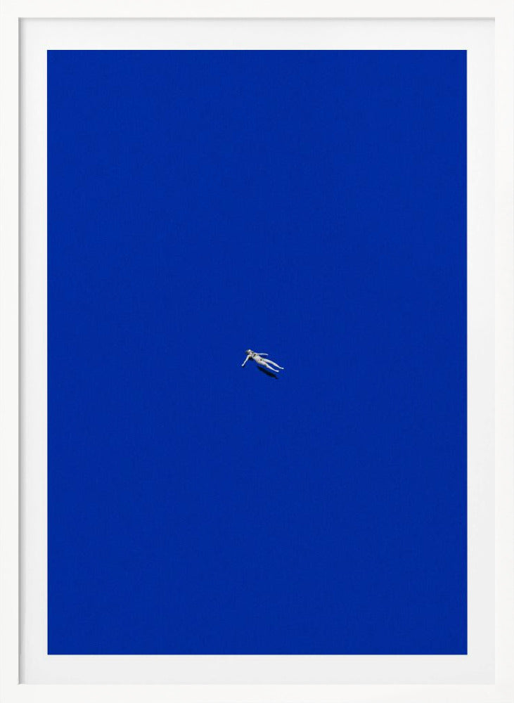 A minimalist and surreal artwork featuring a tiny, pale human figure floating peacefully in the center of an immense, solid, and vibrant blue void, all enclosed within a thin black frame. Wall Art