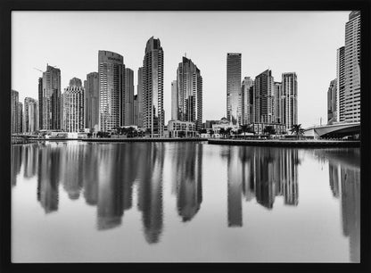 A framed black and white photograph of the Dubai Marina skyline, with its modern skyscrapers perfectly reflected in the calm water of the canal. Decor