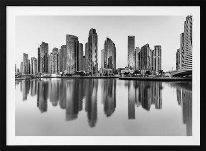 A framed black and white photograph of the Dubai Marina skyline, with its modern skyscrapers perfectly reflected in the calm water of the canal. Decor