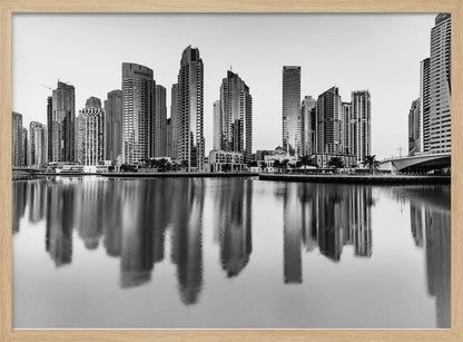 A framed black and white photograph of the Dubai Marina skyline, with its modern skyscrapers perfectly reflected in the calm water of the canal. Decor