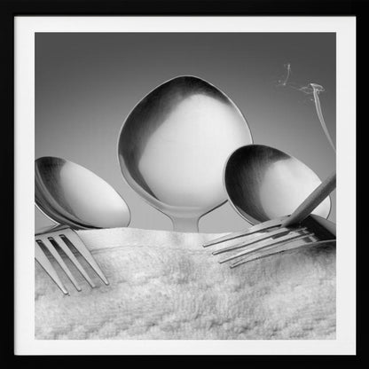 A conceptual black and white photograph in a light wood frame, featuring three spoons standing upright on a white towel, while a fork in the foreground holds a lit, smoking cigarette between its tines. Wall Art