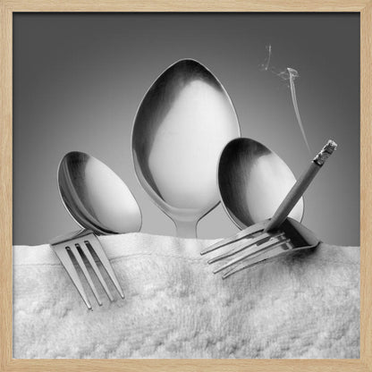 A conceptual black and white photograph in a light wood frame, featuring three spoons standing upright on a white towel, while a fork in the foreground holds a lit, smoking cigarette between its tines. Wall Art