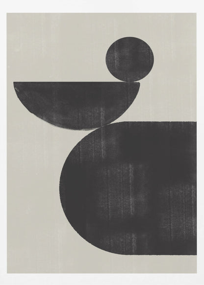 A minimalist abstract artwork featuring three charcoal black shapes stacked against a light beige textured background. At the bottom is a large, rounded shape, on which a semi-circle is balanced. A smaller, full circle rests on top of the semi-circle, creating a sense of precarious balance. The piece is enclosed in a simple black frame. Decor