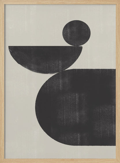 A minimalist abstract artwork featuring three charcoal black shapes stacked against a light beige textured background. At the bottom is a large, rounded shape, on which a semi-circle is balanced. A smaller, full circle rests on top of the semi-circle, creating a sense of precarious balance. The piece is enclosed in a simple black frame. Decor