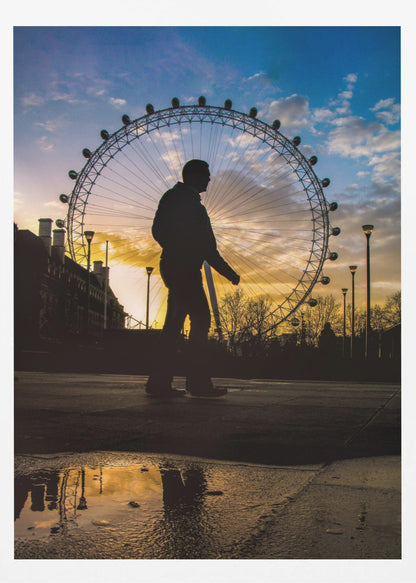 A low-angle shot of a person's silhouette walking past the London Eye at sunset, with the vibrant orange and blue sky reflected in a puddle in the foreground. Decor
