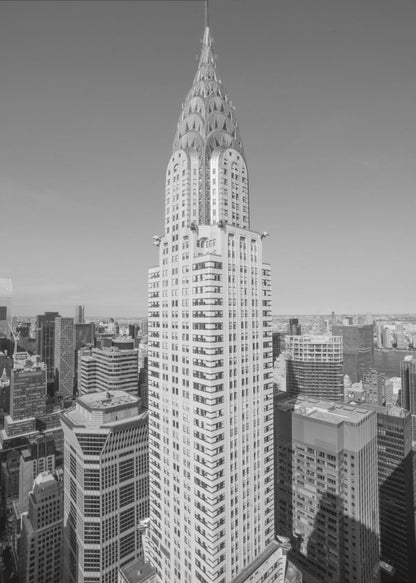 A high-angle, black and white photograph of the iconic Chrysler Building, its Art Deco spire prominently featured against the New York City skyline under a clear sky. Artwork