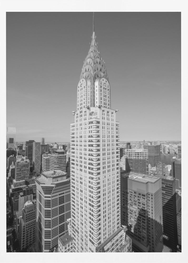 A high-angle, black and white photograph of the iconic Chrysler Building, its Art Deco spire prominently featured against the New York City skyline under a clear sky. Artwork