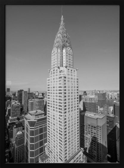 A high-angle, black and white photograph of the iconic Chrysler Building, its Art Deco spire prominently featured against the New York City skyline under a clear sky. Artwork