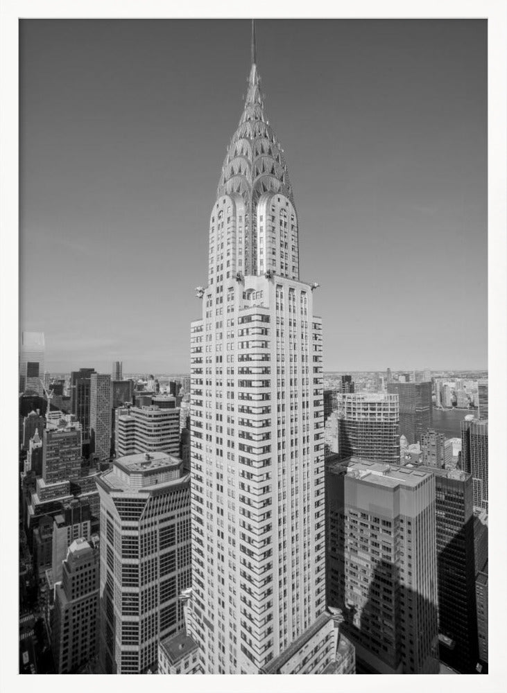 A high-angle, black and white photograph of the iconic Chrysler Building, its Art Deco spire prominently featured against the New York City skyline under a clear sky. Artwork