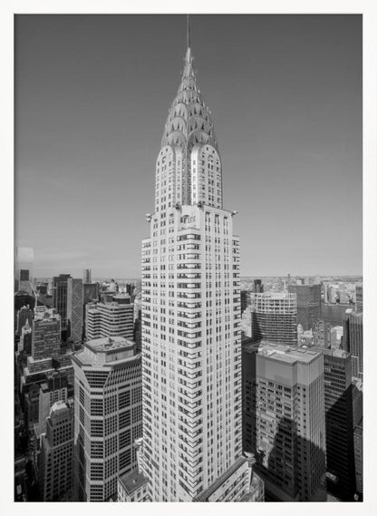 A high-angle, black and white photograph of the iconic Chrysler Building, its Art Deco spire prominently featured against the New York City skyline under a clear sky. Artwork
