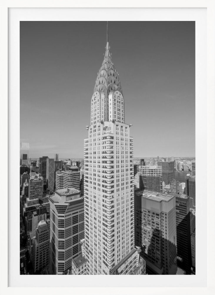 A high-angle, black and white photograph of the iconic Chrysler Building, its Art Deco spire prominently featured against the New York City skyline under a clear sky. Artwork