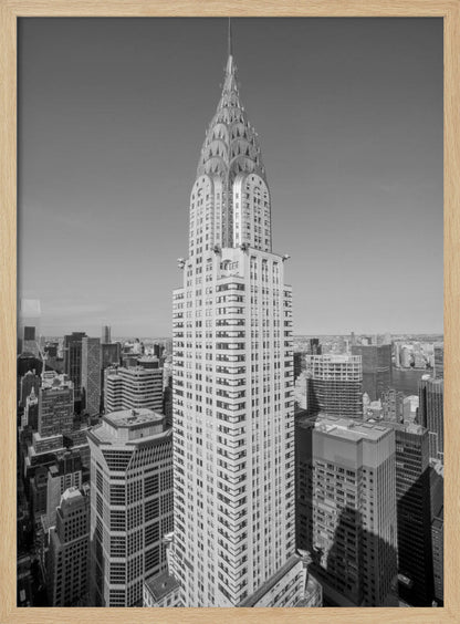 A high-angle, black and white photograph of the iconic Chrysler Building, its Art Deco spire prominently featured against the New York City skyline under a clear sky. Artwork