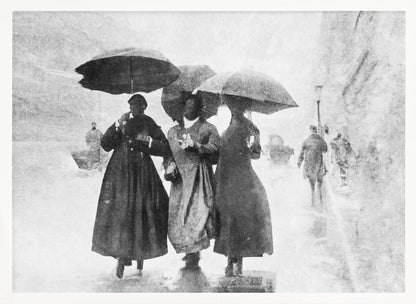 A vintage black and white photograph in a silver frame, depicting three people in long dark coats walking together under umbrellas during a heavy snow or rain storm on a city street. The image has a grainy, textured quality, giving it an old-fashioned, artistic feel. Poster