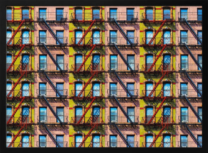A pop-art style repeating pattern of a colorful apartment building facade featuring pink and yellow walls, windows reflecting a blue sky, and a network of black and red fire escapes, enclosed in a silver frame. Artwork