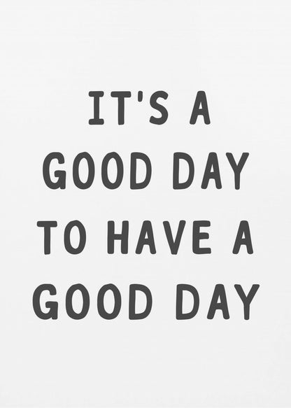 A framed black and white art print with the phrase 'IT'S A GOOD DAY TO HAVE A GOOD DAY' in a bold, dark gray, sans-serif font. Artwork