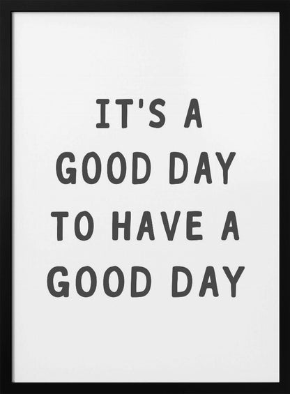 A framed black and white art print with the phrase 'IT'S A GOOD DAY TO HAVE A GOOD DAY' in a bold, dark gray, sans-serif font. Artwork
