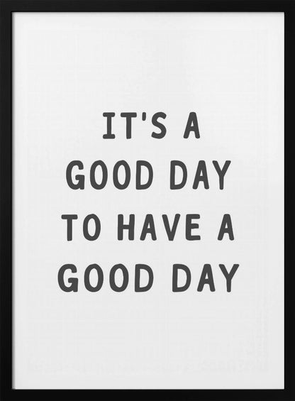 A framed black and white art print with the phrase 'IT'S A GOOD DAY TO HAVE A GOOD DAY' in a bold, dark gray, sans-serif font. Artwork